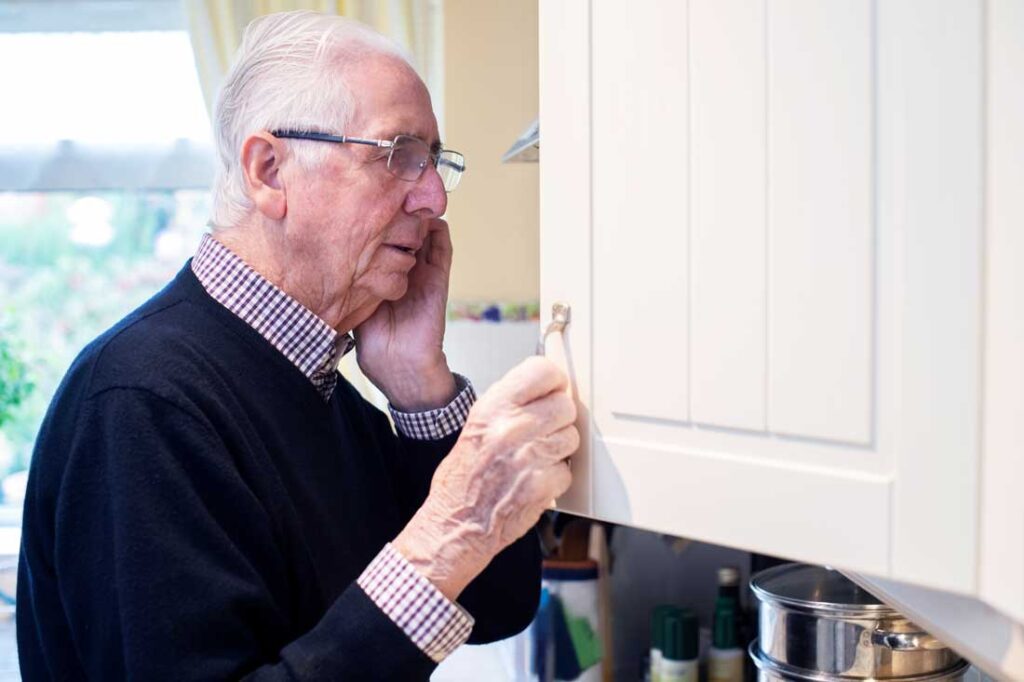 Elderly Man Looking In Cupboard