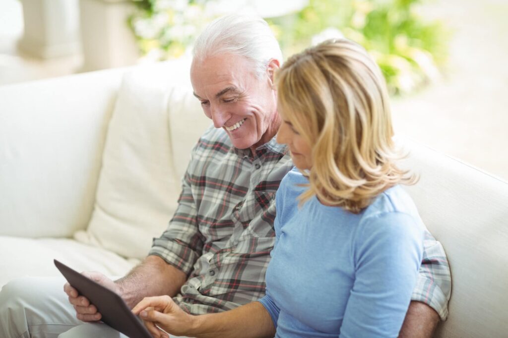 Senior couple using digital tablet in living room