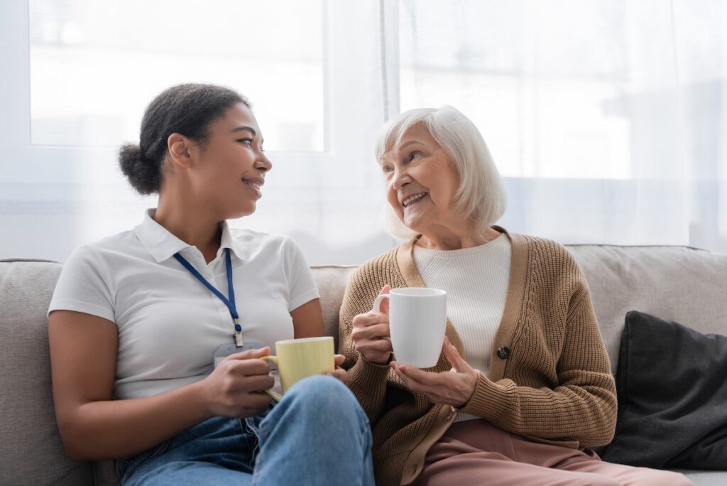 Caregiver having a cup of coffee with an older female senior living resident
