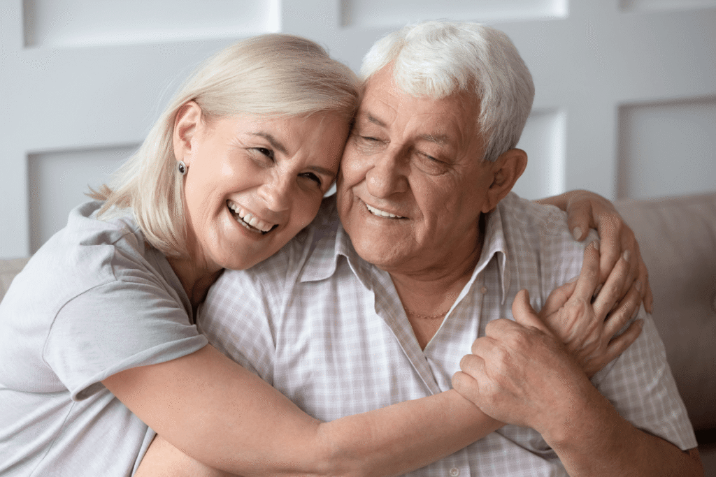 Head shot close up portrait happy grey haired middle aged woman snuggling to smiling older husband, enjoying tender moment at home. Bonding loving old family couple embracing, feeling happiness.